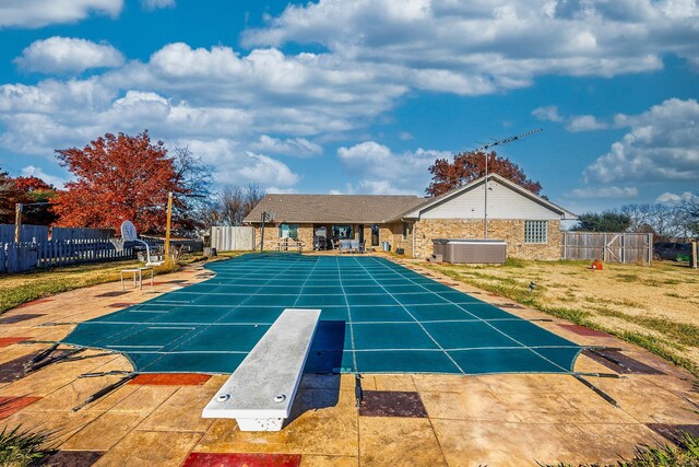 view of swimming pool featuring a diving board, central AC unit, and a patio area