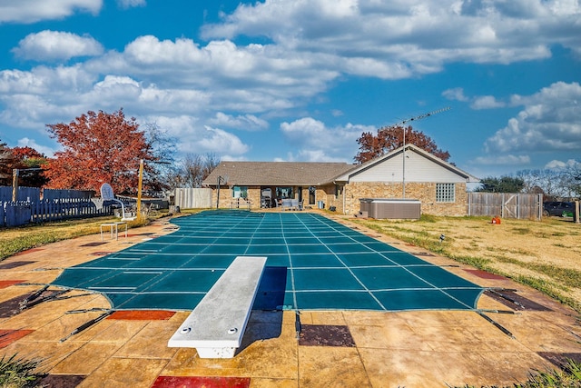 view of swimming pool featuring a diving board, central air condition unit, and a patio area