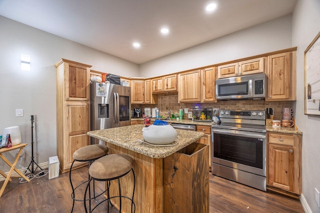 kitchen featuring a center island, light stone counters, dark hardwood / wood-style floors, decorative backsplash, and appliances with stainless steel finishes