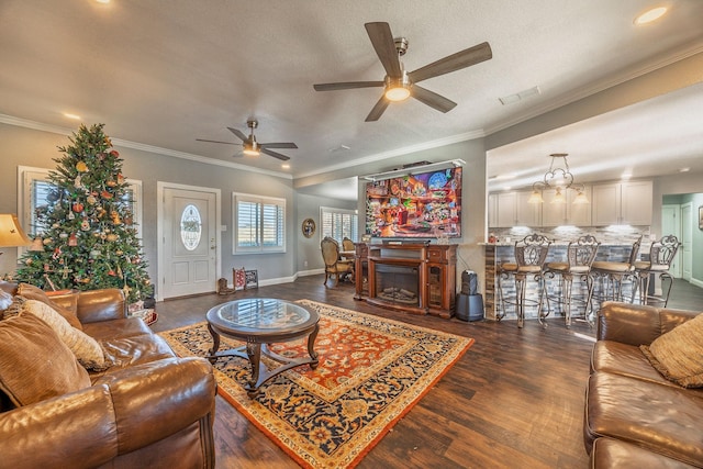 living room with ceiling fan with notable chandelier, dark hardwood / wood-style flooring, ornamental molding, and a textured ceiling