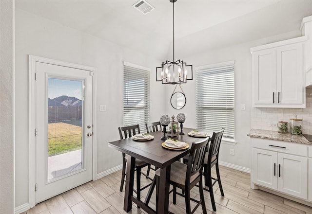 dining area featuring light hardwood / wood-style floors, an inviting chandelier, and lofted ceiling