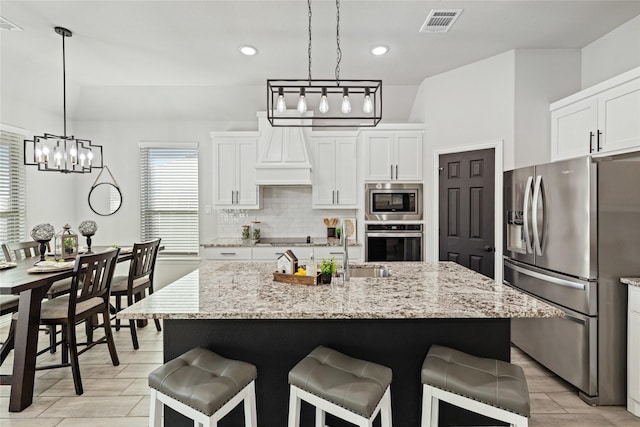 kitchen with a center island with sink, white cabinets, and appliances with stainless steel finishes