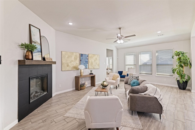 living room with ceiling fan, a tile fireplace, and light hardwood / wood-style flooring