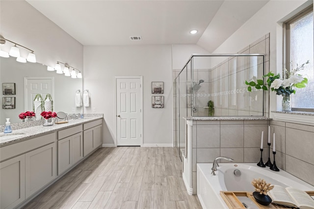 bathroom featuring hardwood / wood-style floors, vanity, lofted ceiling, and shower with separate bathtub