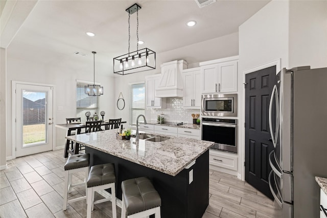 kitchen featuring a healthy amount of sunlight, a kitchen island with sink, sink, and appliances with stainless steel finishes