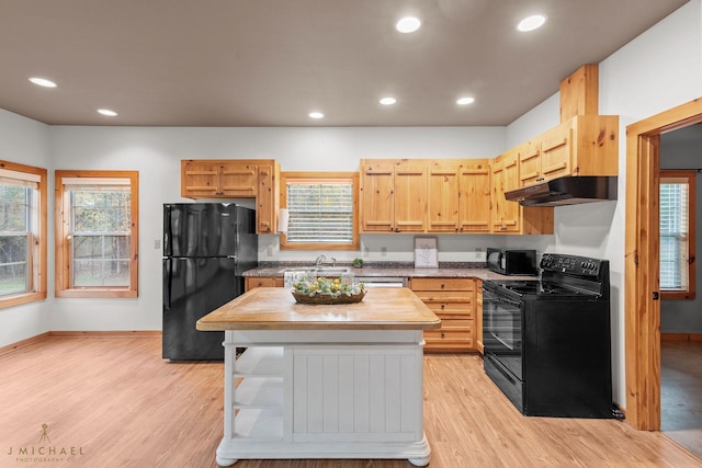 kitchen with plenty of natural light, light hardwood / wood-style floors, light brown cabinets, and black appliances