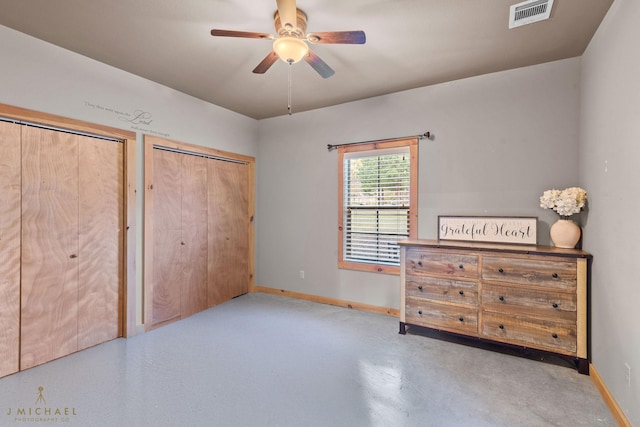 unfurnished bedroom featuring ceiling fan and multiple closets