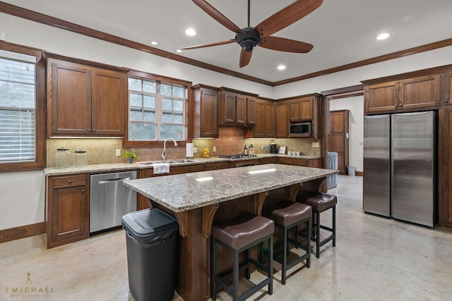 kitchen featuring sink, appliances with stainless steel finishes, backsplash, a kitchen breakfast bar, and a center island