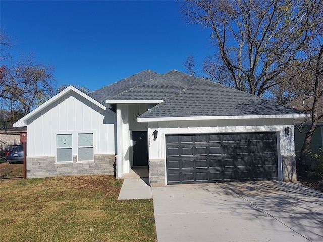 view of front of house with an attached garage, driveway, roof with shingles, a front lawn, and board and batten siding