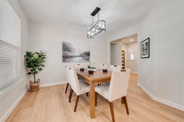 dining room with a notable chandelier, light wood-style flooring, and baseboards