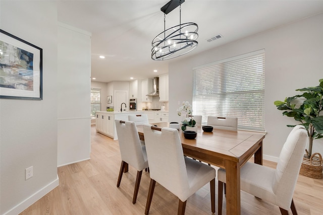 dining space with light wood finished floors, recessed lighting, visible vents, and baseboards