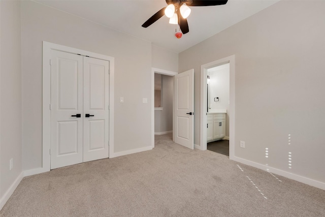 unfurnished bedroom with baseboards, a ceiling fan, ensuite bath, carpet flooring, and a closet