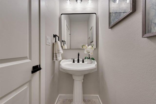 bathroom featuring a textured wall and baseboards