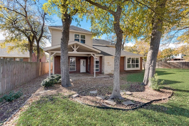 view of front of property with a fenced backyard, roof with shingles, a front lawn, and brick siding