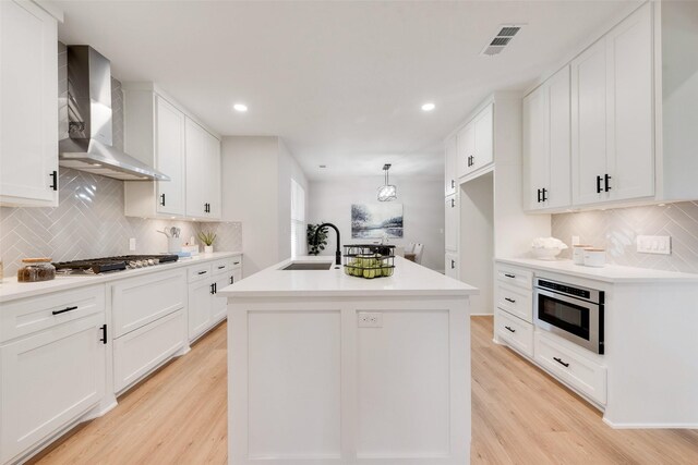 kitchen featuring appliances with stainless steel finishes, an island with sink, white cabinetry, and sink