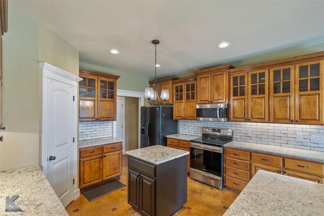 kitchen featuring tasteful backsplash, decorative light fixtures, a kitchen island, light stone counters, and stainless steel appliances