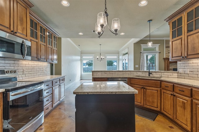 kitchen featuring appliances with stainless steel finishes, sink, pendant lighting, a notable chandelier, and a center island