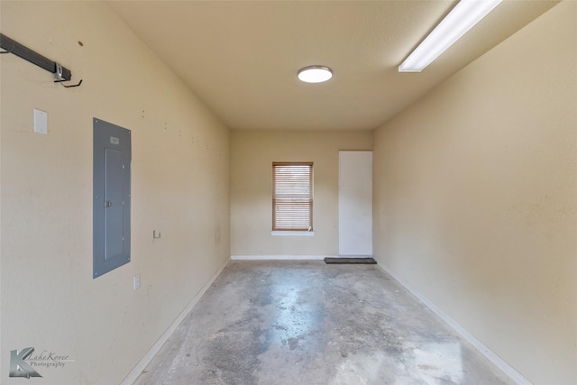 empty room with electric panel and concrete flooring