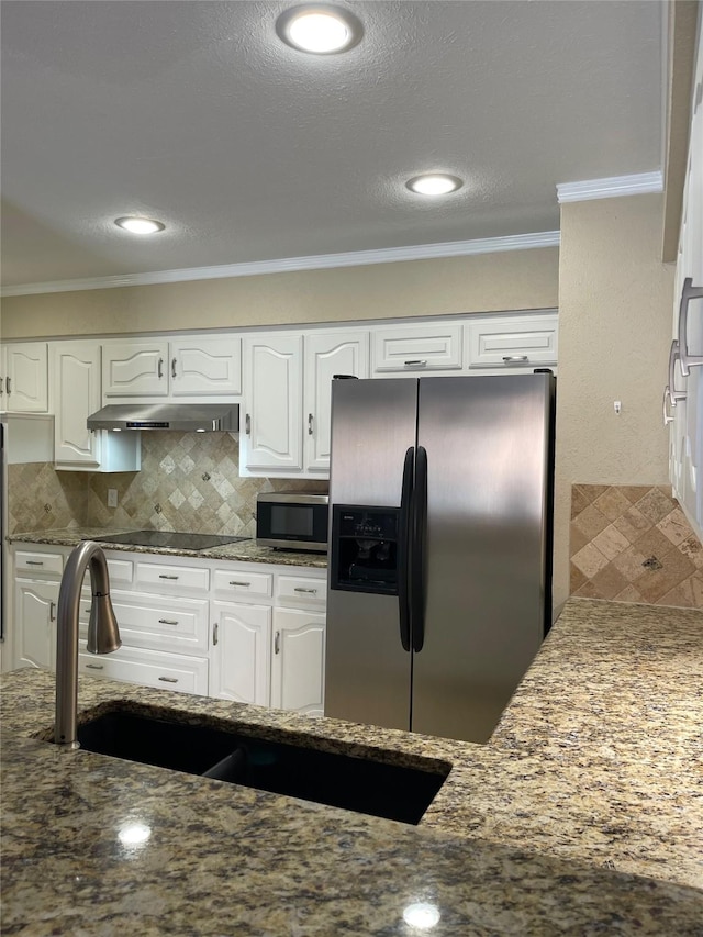 kitchen with backsplash, crown molding, dark stone counters, white cabinets, and appliances with stainless steel finishes