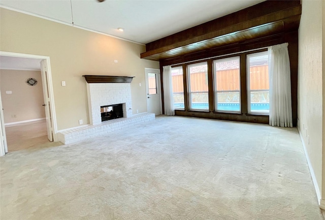 unfurnished living room with beamed ceiling, crown molding, light carpet, and a brick fireplace