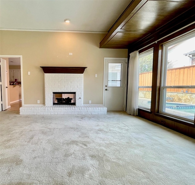 unfurnished living room featuring wood ceiling, ornamental molding, light colored carpet, and a brick fireplace