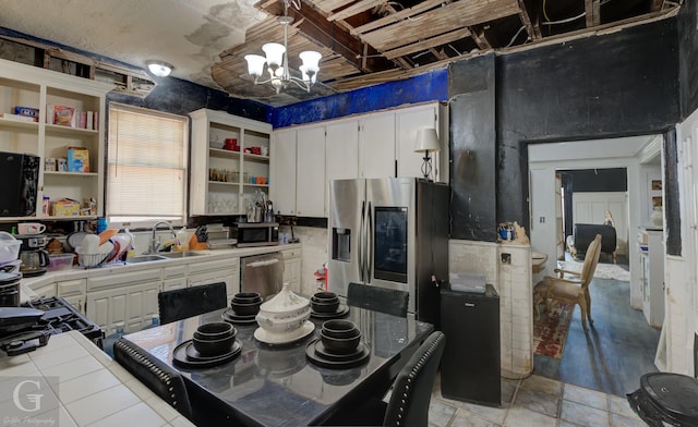 kitchen with an inviting chandelier, sink, tile counters, white cabinetry, and stainless steel appliances