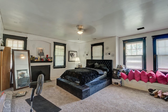 carpeted bedroom with multiple windows and ceiling fan