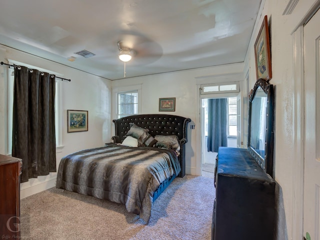 bedroom with multiple windows, light colored carpet, and ceiling fan