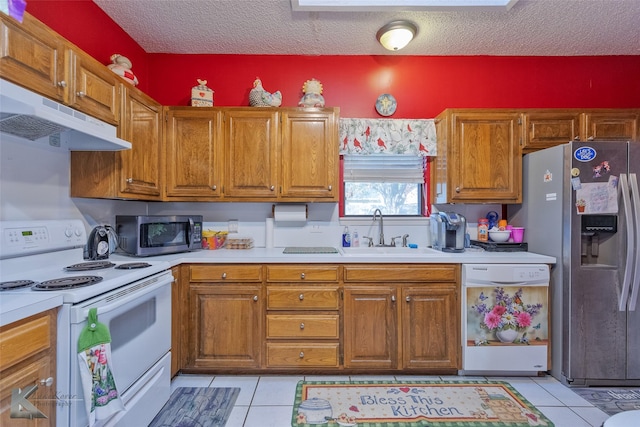 kitchen with sink, light tile patterned floors, a textured ceiling, and appliances with stainless steel finishes