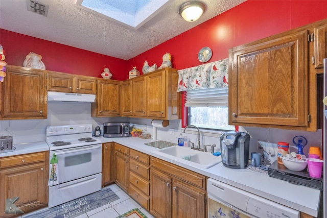 kitchen featuring a textured ceiling, white appliances, sink, and a skylight