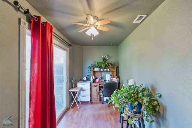 home office featuring a textured ceiling, light hardwood / wood-style flooring, and ceiling fan