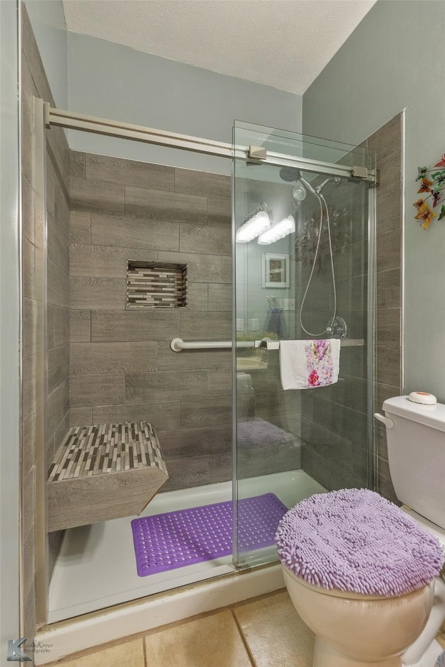 bathroom featuring a textured ceiling, toilet, and an enclosed shower