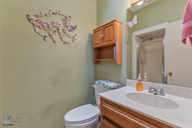 bathroom featuring a shower with door, vanity, and toilet