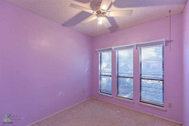 unfurnished room featuring ceiling fan, light colored carpet, and a textured ceiling