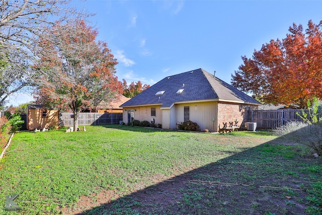 rear view of house with central AC, a yard, and a storage unit