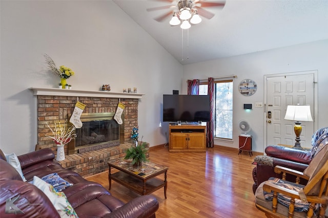 living room with ceiling fan, a fireplace, high vaulted ceiling, and light hardwood / wood-style floors