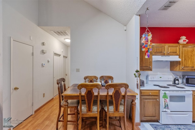 kitchen featuring white range with electric cooktop, light hardwood / wood-style floors, a textured ceiling, and vaulted ceiling