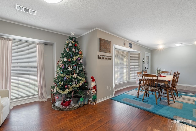 dining room featuring dark hardwood / wood-style flooring, ornamental molding, and a textured ceiling