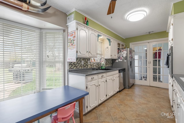 kitchen with french doors, a textured ceiling, stainless steel appliances, sink, and white cabinets