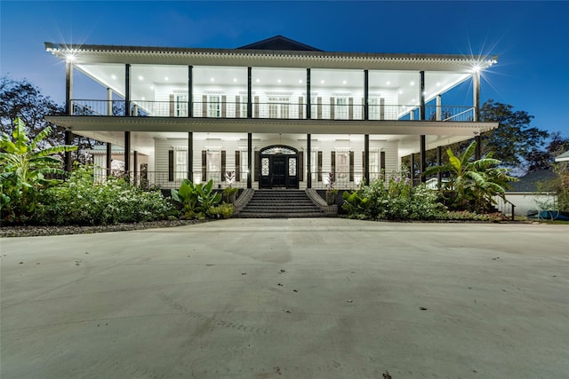 view of front of home featuring covered porch, a balcony, and french doors