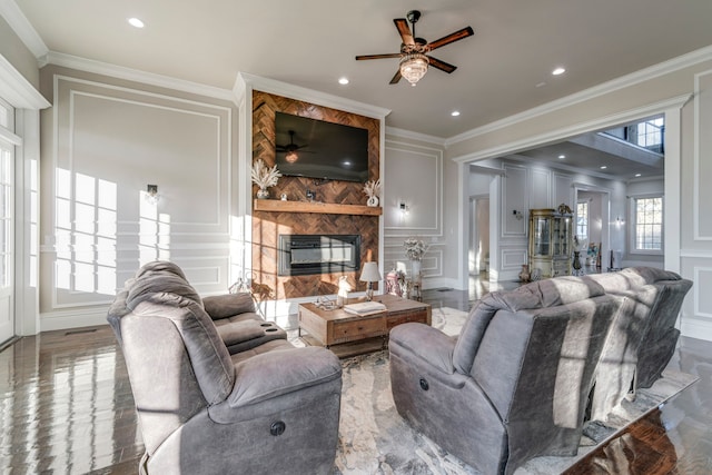 living room featuring a fireplace, hardwood / wood-style flooring, ceiling fan, and crown molding