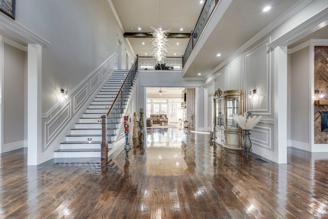 entryway with crown molding, hardwood / wood-style floors, and a high ceiling