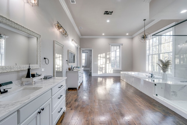 bathroom with hardwood / wood-style flooring, ornamental molding, tiled bath, and vanity