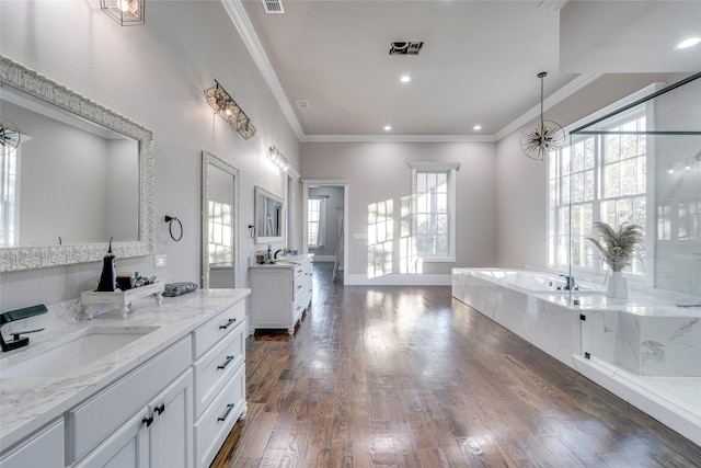 bathroom with a relaxing tiled tub, ornamental molding, vanity, and hardwood / wood-style flooring