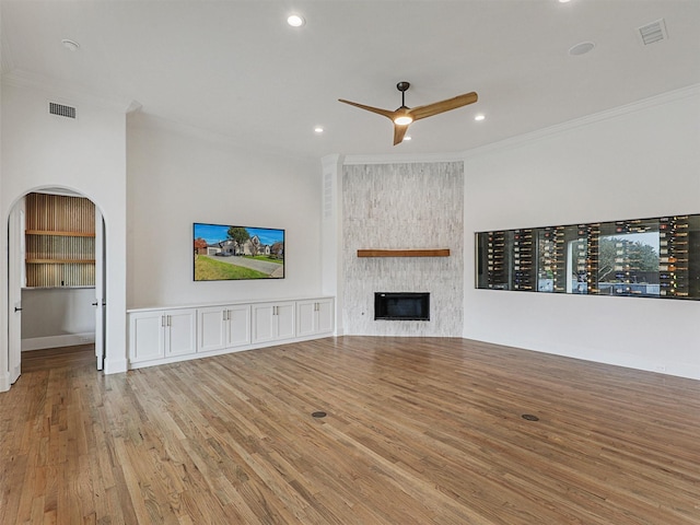 unfurnished living room with a fireplace, light wood-type flooring, ceiling fan, and ornamental molding