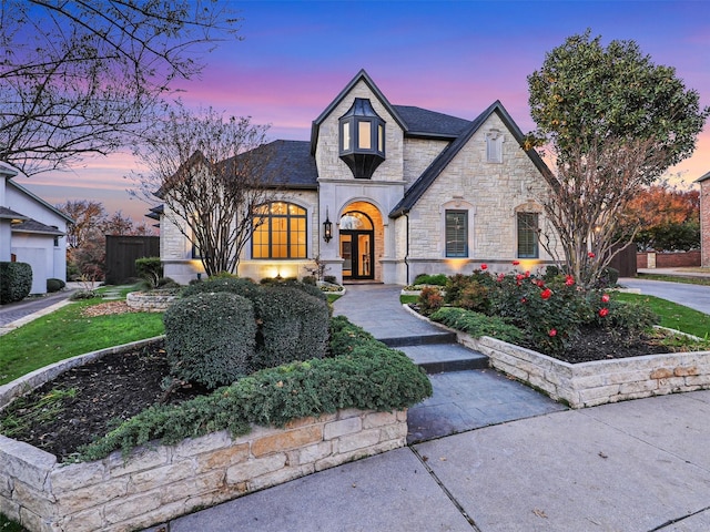 view of front of house with stone siding, french doors, and fence