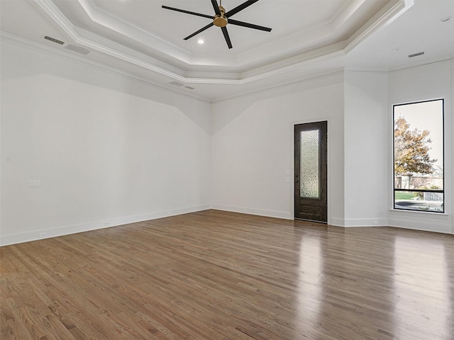 unfurnished room featuring wood-type flooring, a tray ceiling, ceiling fan, and crown molding