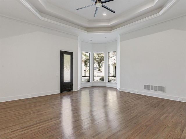 unfurnished room with a raised ceiling, ceiling fan, ornamental molding, and dark hardwood / wood-style flooring