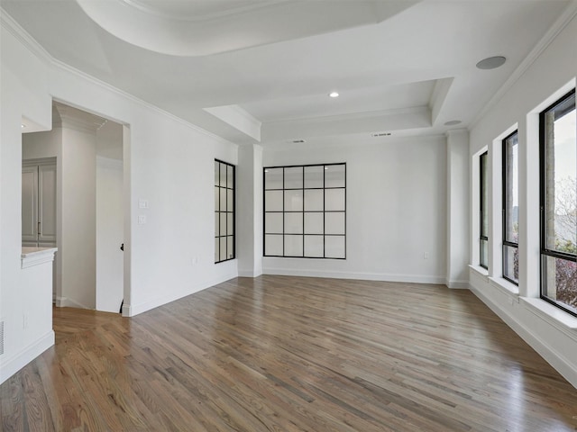 unfurnished room featuring a raised ceiling, crown molding, and hardwood / wood-style flooring