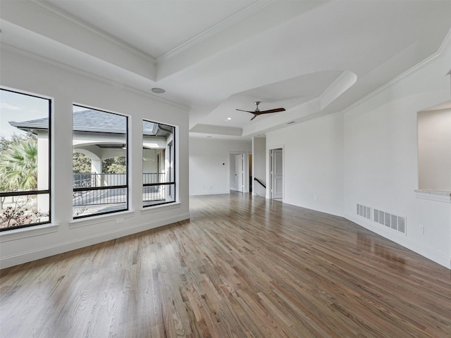 unfurnished living room featuring hardwood / wood-style floors, a raised ceiling, ceiling fan, and ornamental molding